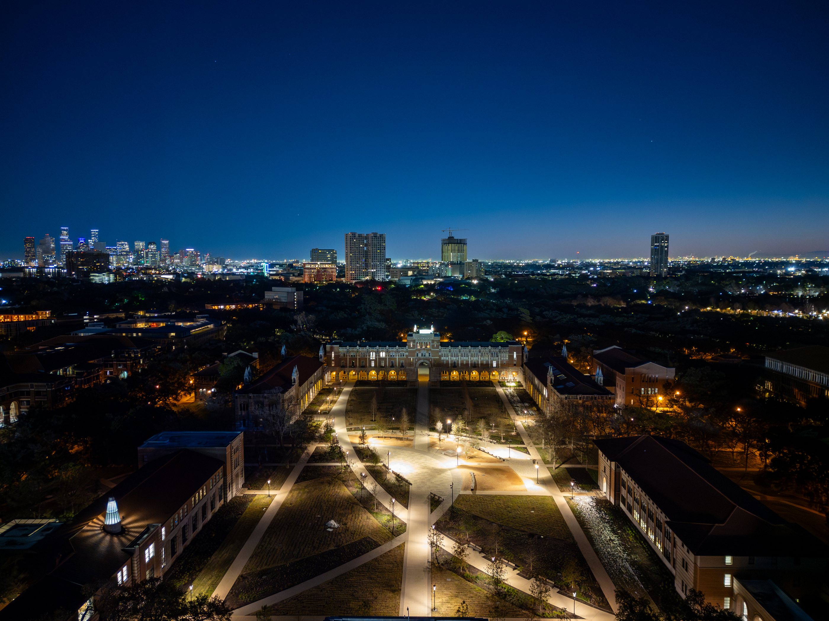 Rice University campus at night, with the Houston skyline